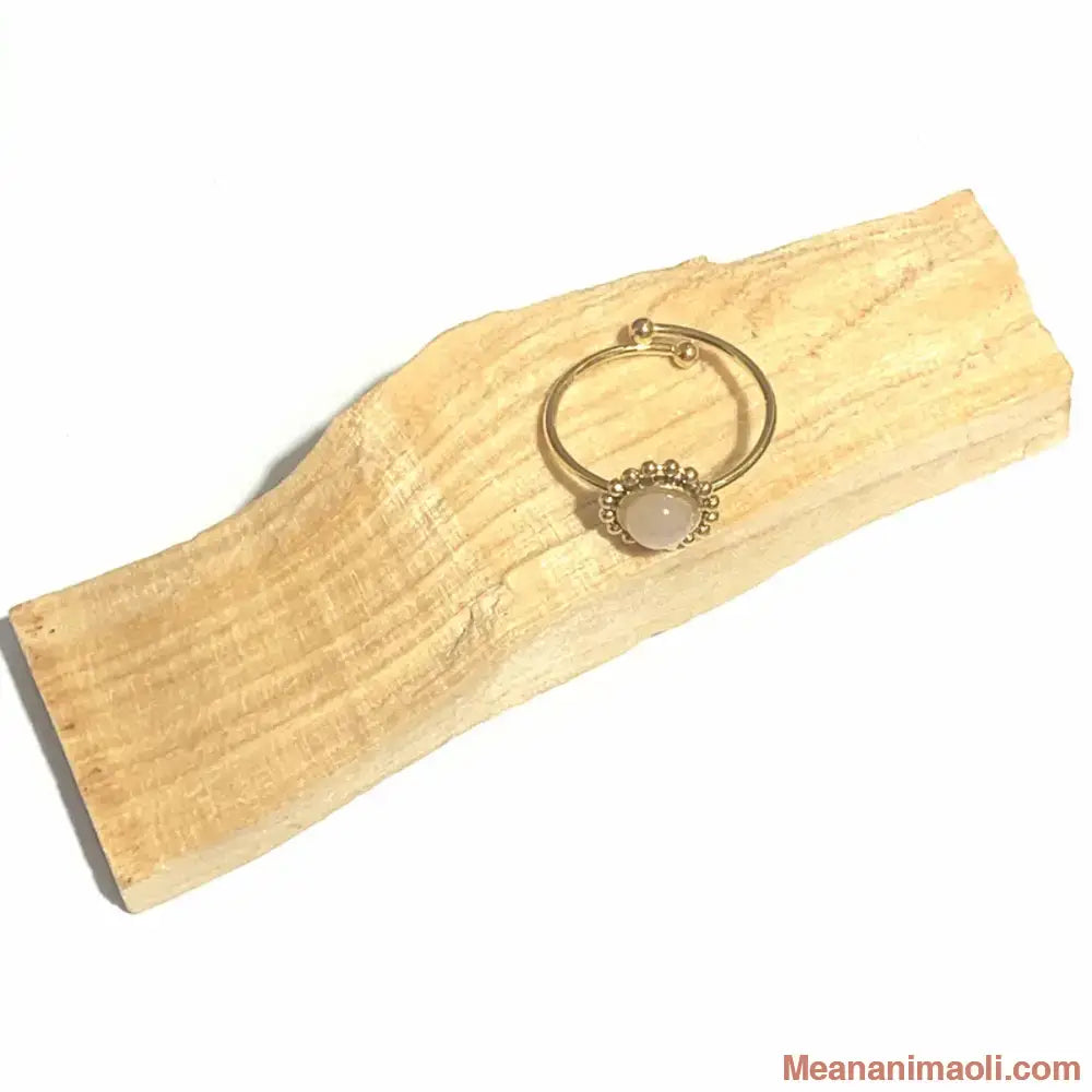 Bague réglable en acier inoxydable doré avec pierre naturelle quartz rose, posée sur un bâton de palo santo
