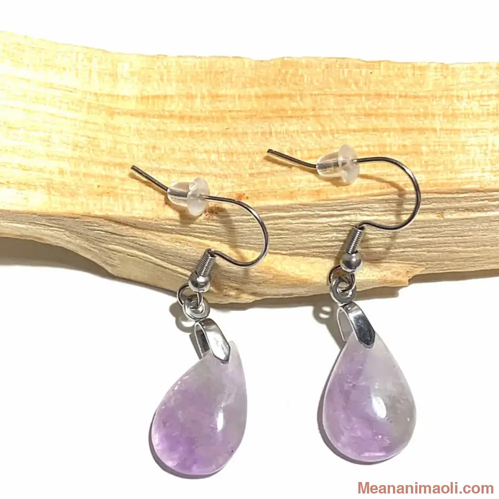 Paire de boucles d'oreilles élégantes en acier inoxydable argenté avec pierre naturelle Améthyste, posées sur un bâton de Palo Santo