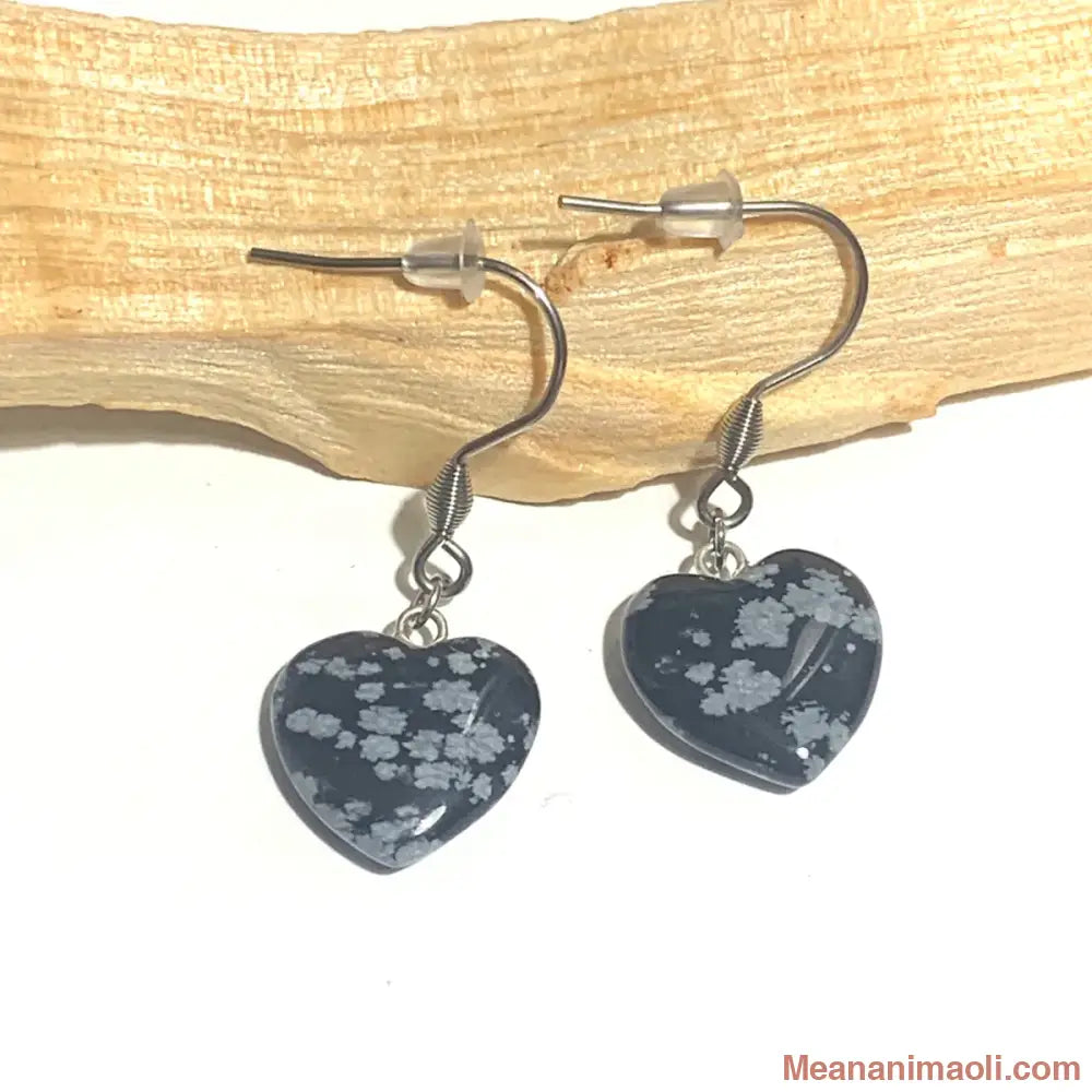 Paire de boucles d'oreilles en Obsidienne Flocon de Neige en forme de cœur, acier inoxydable argenté, posées sur un bâton de Palo Santo