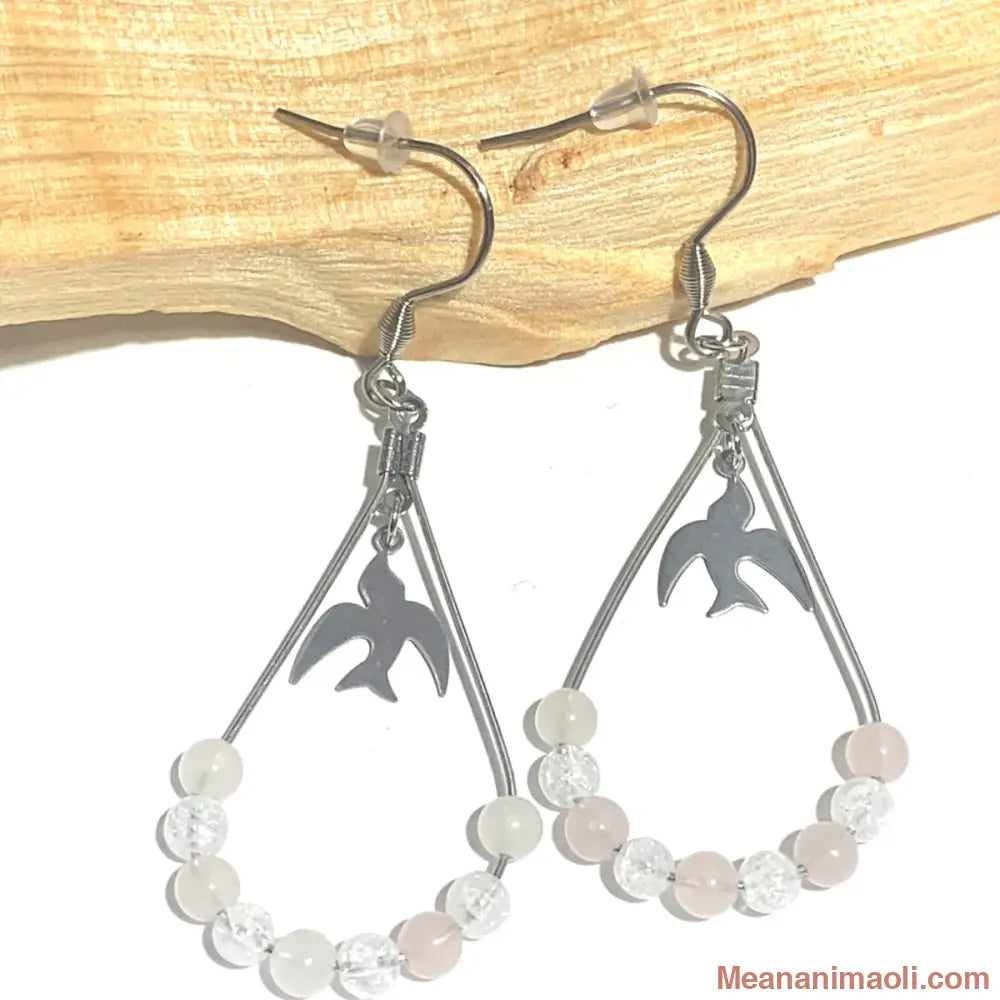Paire de boucles d'oreilles en Quartz Rose et Cristal de Roche Craquelé, acier inoxydable argenté, posées sur un bâton de Palo Santo