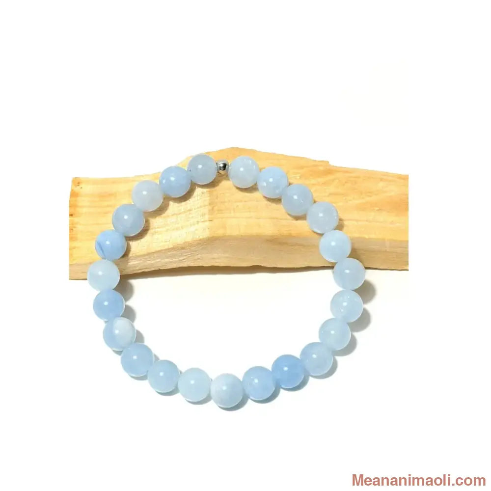 Bracelet en perles 8 mm rondes de Calcédoine Bleue pastel avec une perle centrale en acier inoxydable argenté posé sur du bois de Palo Santo - MEANANIMAOLI