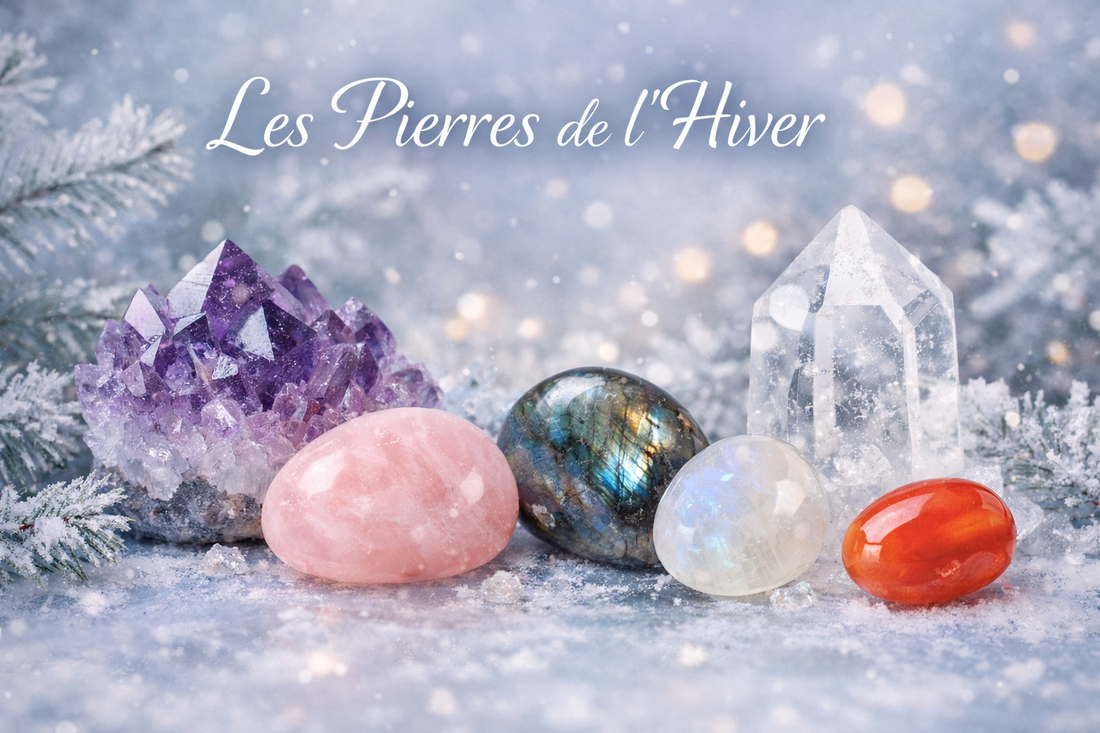 Pierres de lithothérapie pour l'hiver : améthyste, quartz rose, cornaline, labradorite et pierre de lune posées sur une surface de glace avec un décor hivernal givré