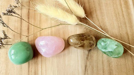 Sélection de 4 pierres naturelles de printemps (Aventurine, Quartz Rose, Fluorite et Citrine) posées sur un fond en bois avec des fleurs séchées - MEANANIMAOLI