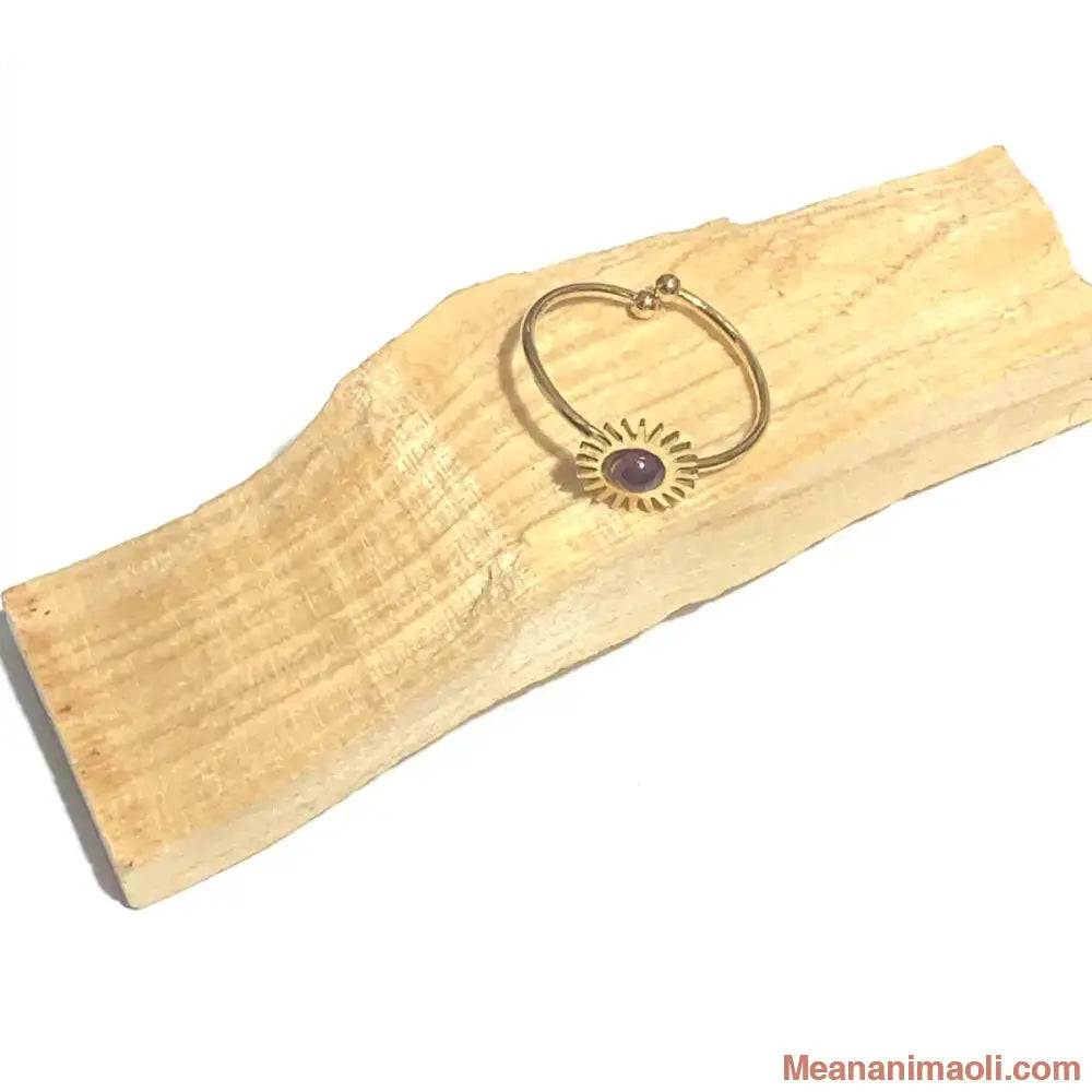 Bague réglable en acier inoxydable doré avec pierre naturelle grenat, posée sur un bâton de palo santo