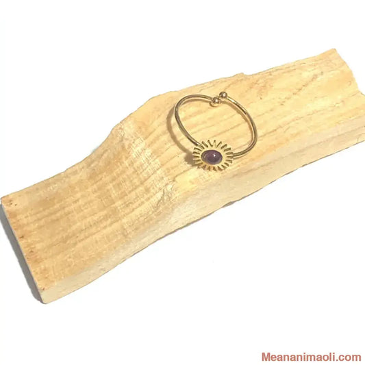 Bague réglable en acier inoxydable doré avec pierre naturelle grenat, posée sur un bâton de palo santo