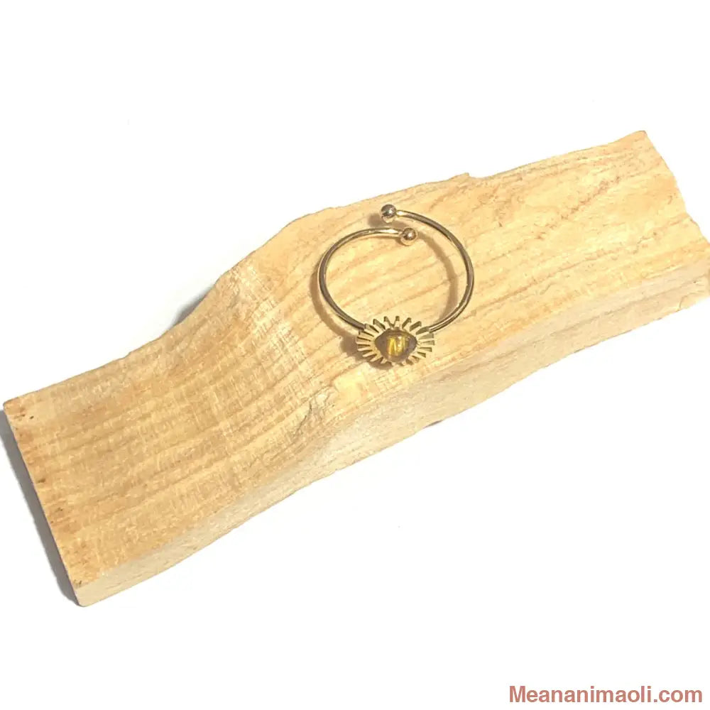 Bague réglable en acier inoxydable doré avec pierre naturelle oeil de tigre, posée sur un bâton de palo santo