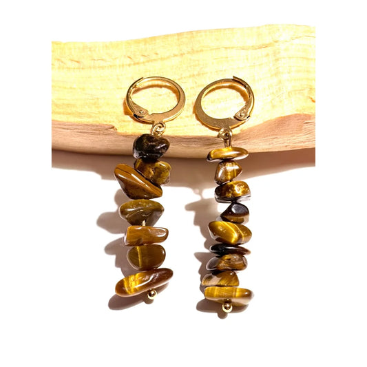 Boucles d'oreilles pendantes en acier inoxydable doré avec perles chips d'Oeil de Tigre naturel posées sur un morceau de bois Palo Santo, une création MEANANIMAOLI