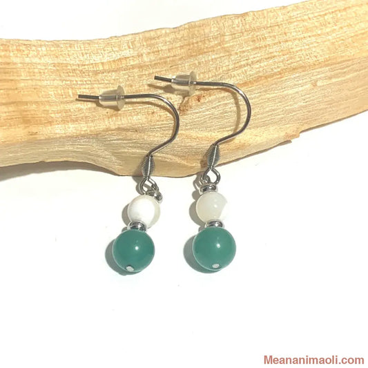 Paire de boucles d'oreilles en acier inoxydable argenté avec perles de Nacre et Aventurine Verte naturelle, posées sur un bâton de Palo Santo.