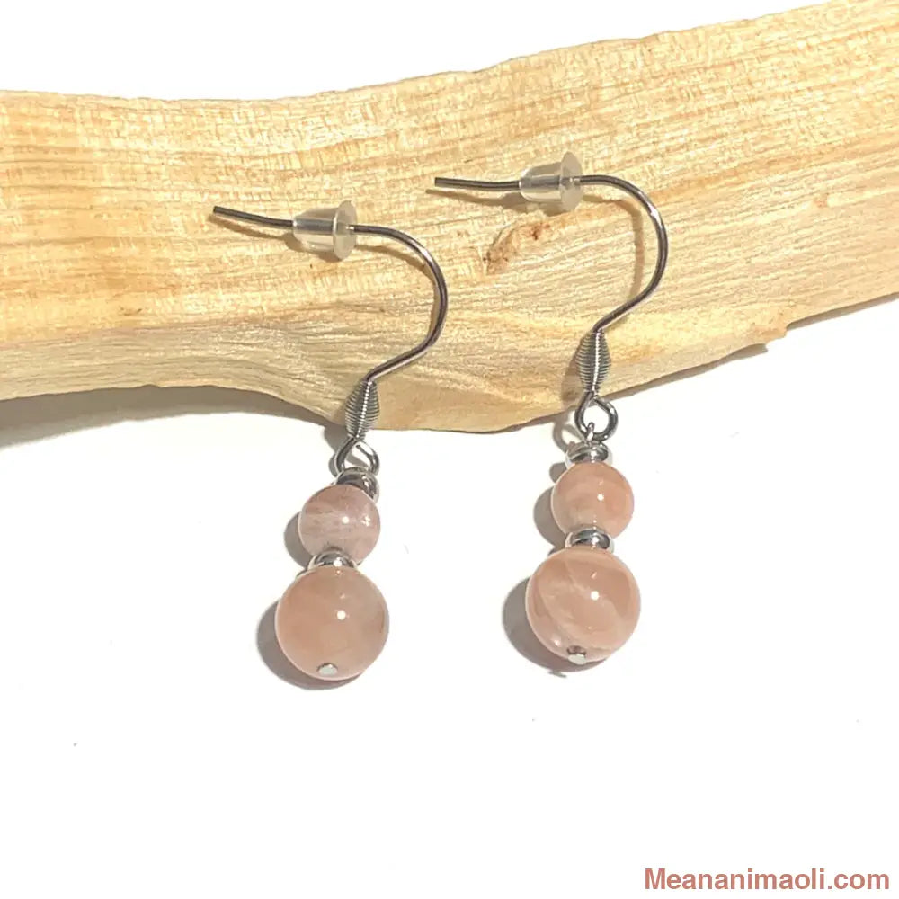 Paire de boucles d'oreilles en acier inoxydable argenté avec pierre naturelle Pierre du Soleil, posées sur un bâton de Palo Santo