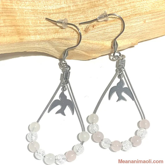 Paire de boucles d'oreilles en Quartz Rose et Cristal de Roche Craquelé, acier inoxydable argenté, posées sur un bâton de Palo Santo