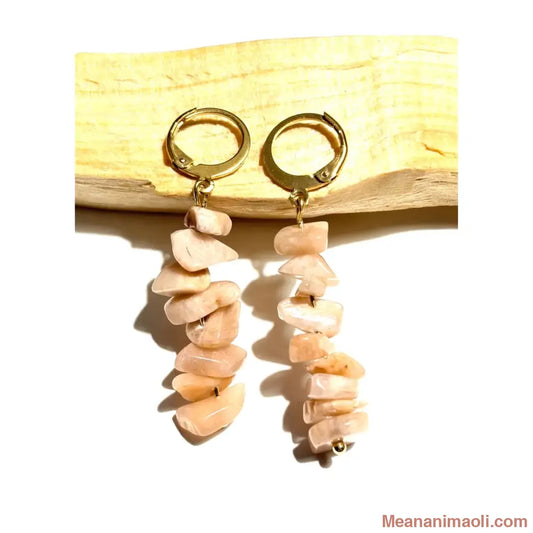 Boucles d'oreilles pendantes en acier inoxydable doré avec perles chips de Pierre du Soleil naturelle posées sur un morceau de bois Palo Santo, une création MEANANIMAOLI