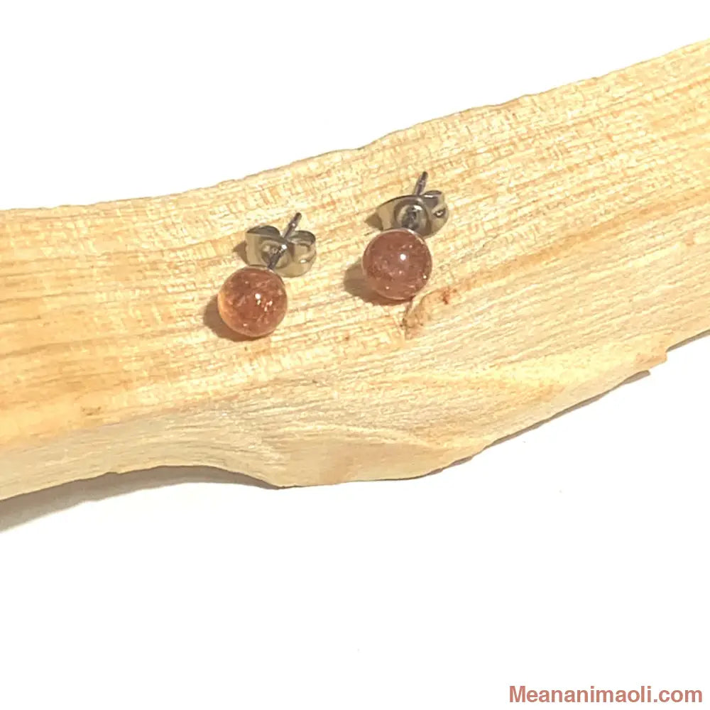 Paire de boucles d'oreilles en acier inoxydable argenté avec pierre naturelle Pierre du Soleil, posées sur un bâton de Palo Santo