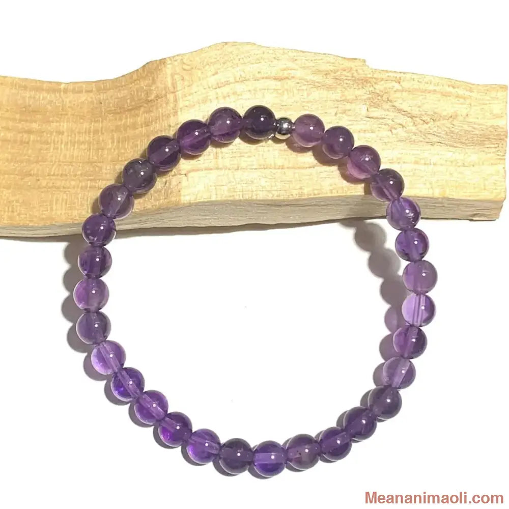 Bracelet pierre naturelle en Améthyste 6mm, perles acier inoxydable argenté posé sur un bâton de palo santo.