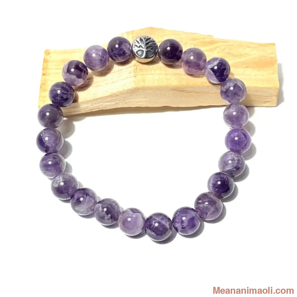 Bracelet en perles de 10 mm Améthyste Chevron naturelle et charm Arbre de Vie en acier argenté, posé sur un bois palo santo