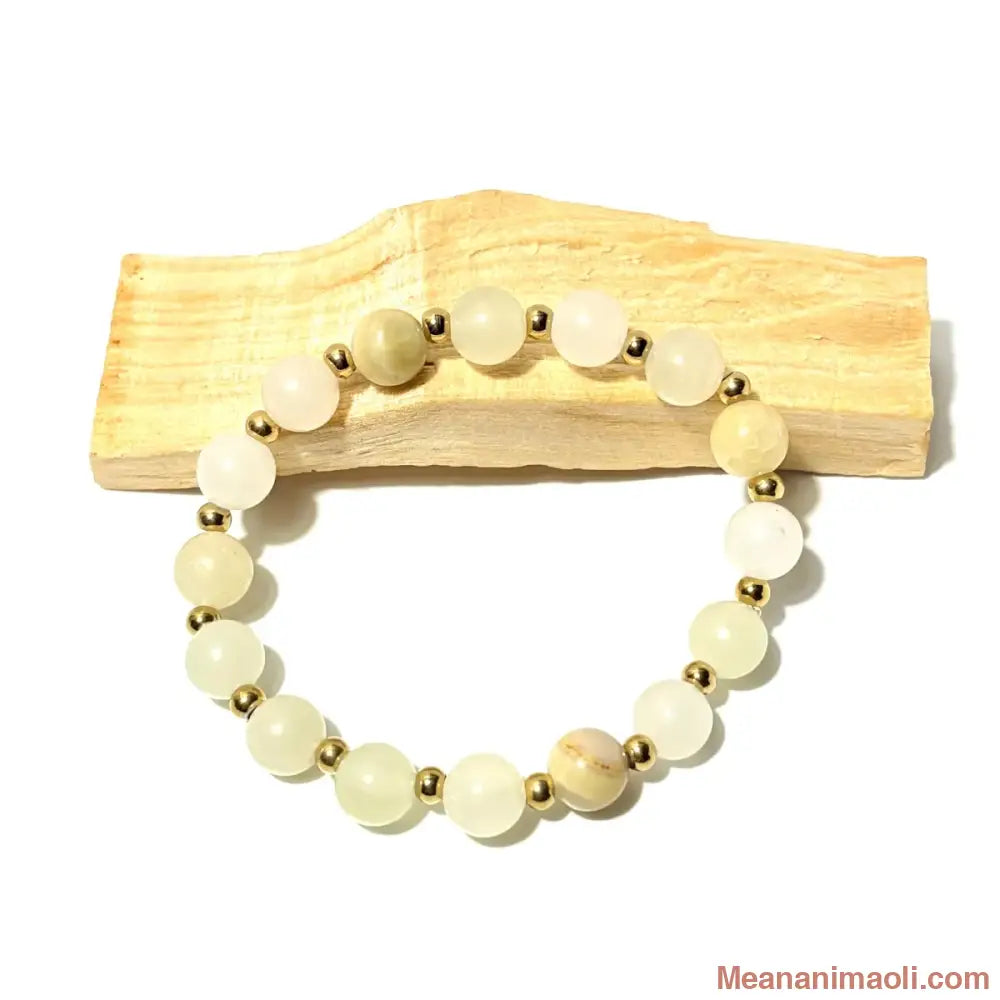 Bracelet en perles de 8 mm Aragonite naturelle et perles acier inoxydable doré posé sur un bois palo santo