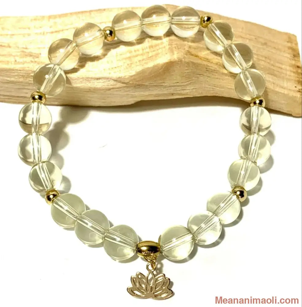 Bracelet Citrine 8 mm avec breloque Fleur de Lotus en acier inoxydable doré posé sur un batôn de Palo Santo.