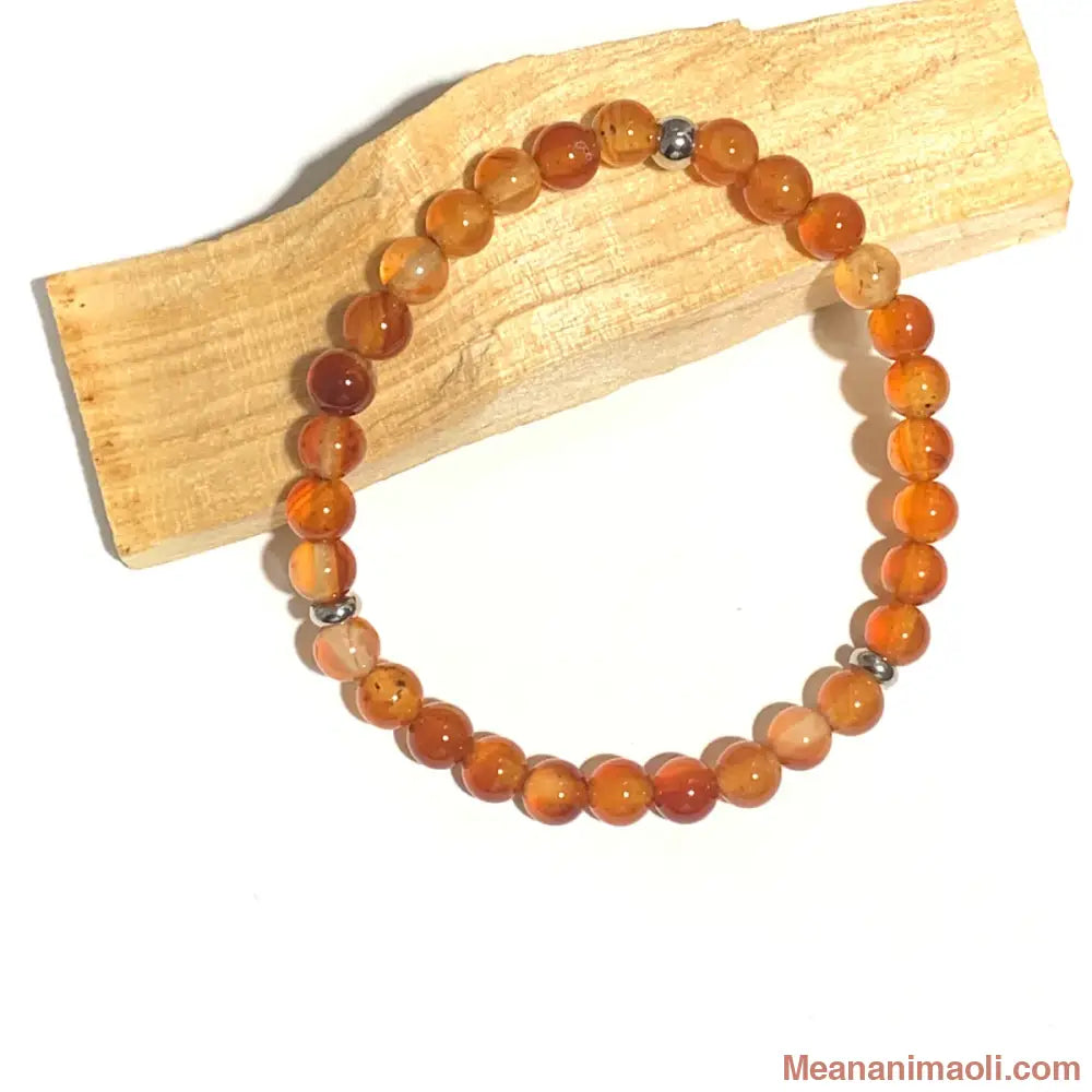 Bracelet Cornaline 6mm, perles acier inoxydable argenté posé sur un bâton palo santo.