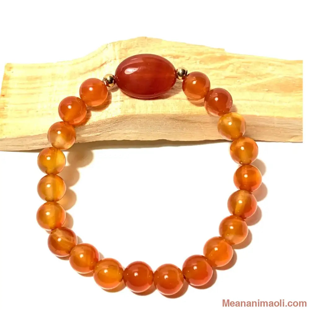 Bracelet de lithothérapie en perles de Cornaline orange de 8 mm avec perle centrale ovale, posé sur du bois de Palo Santo, MEANANIMAOLI