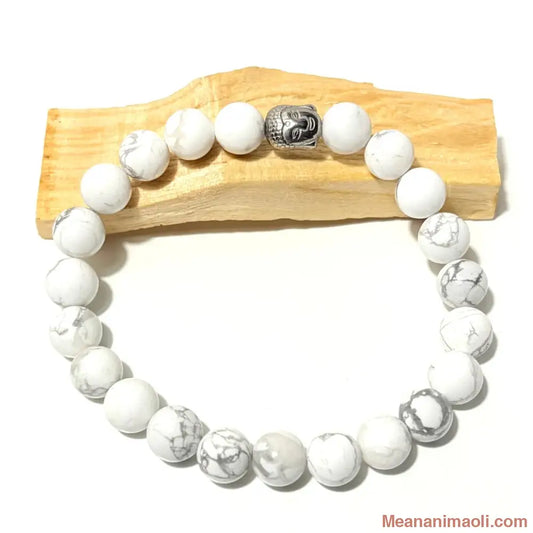 Bracelet en perles de 10 mm Howlite naturelle et charm Bouddha en acier inoxydable argenté posé sur un bois palo santo