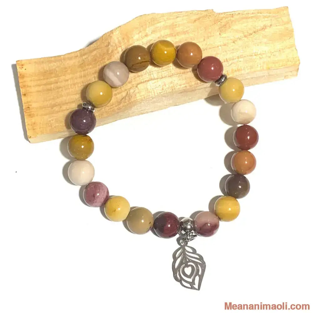 Bracelet Jaspe Mokaïte 8mm et Plume de Paon argentée, posé sur bâton de Palo Santo. Idéal pour la vitalité, l'ancrage, la protection et le voyage.