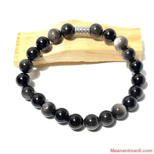 Bracelet en perles de 10 mm Obsidienne Argentée naturelle posé sur un bois palo santo