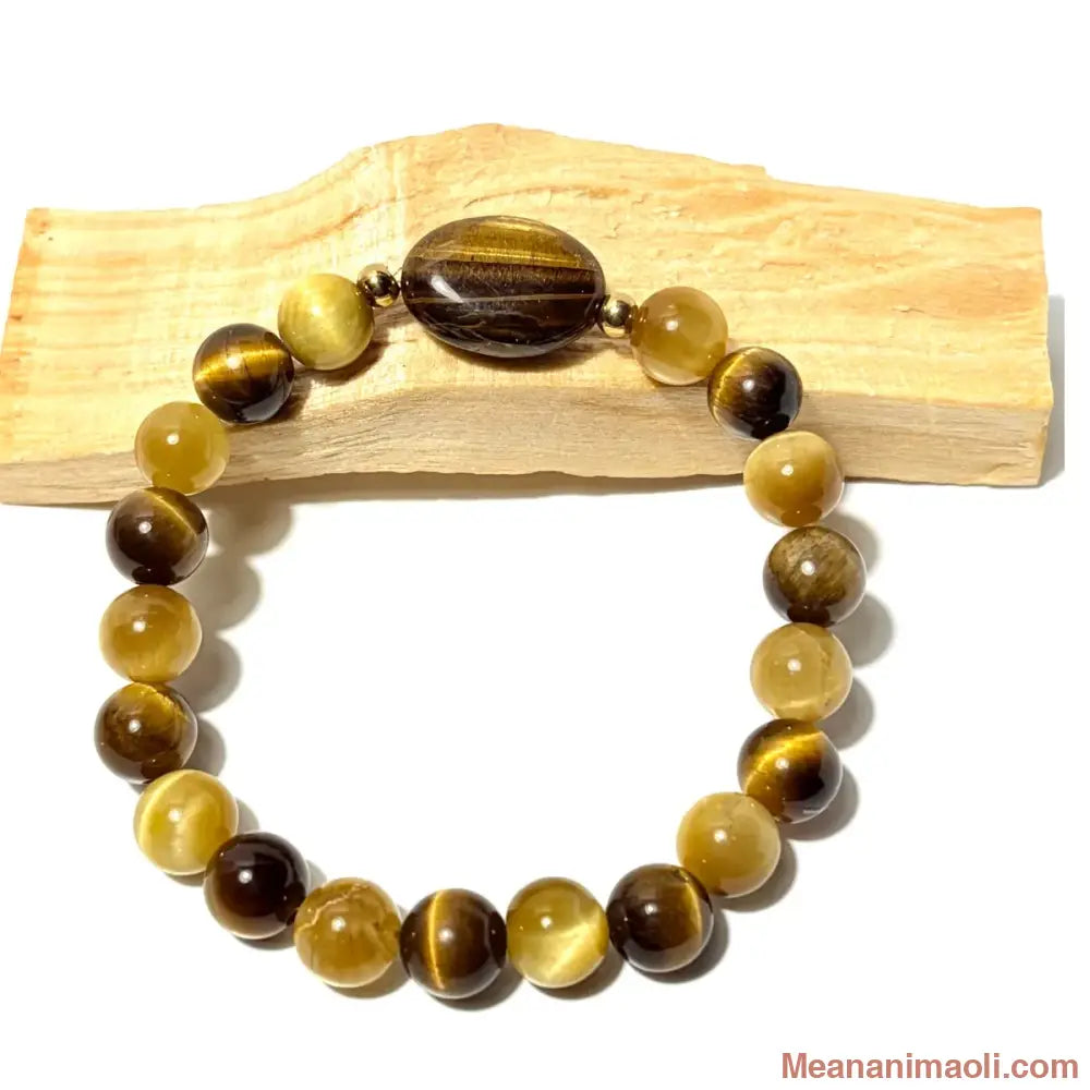 Bracelet de lithothérapie en perles d'Oeil de Tigre doré et marron de 8 mm avec perle centrale ovale, posé sur du bois, boutique MEANANIMAOLI