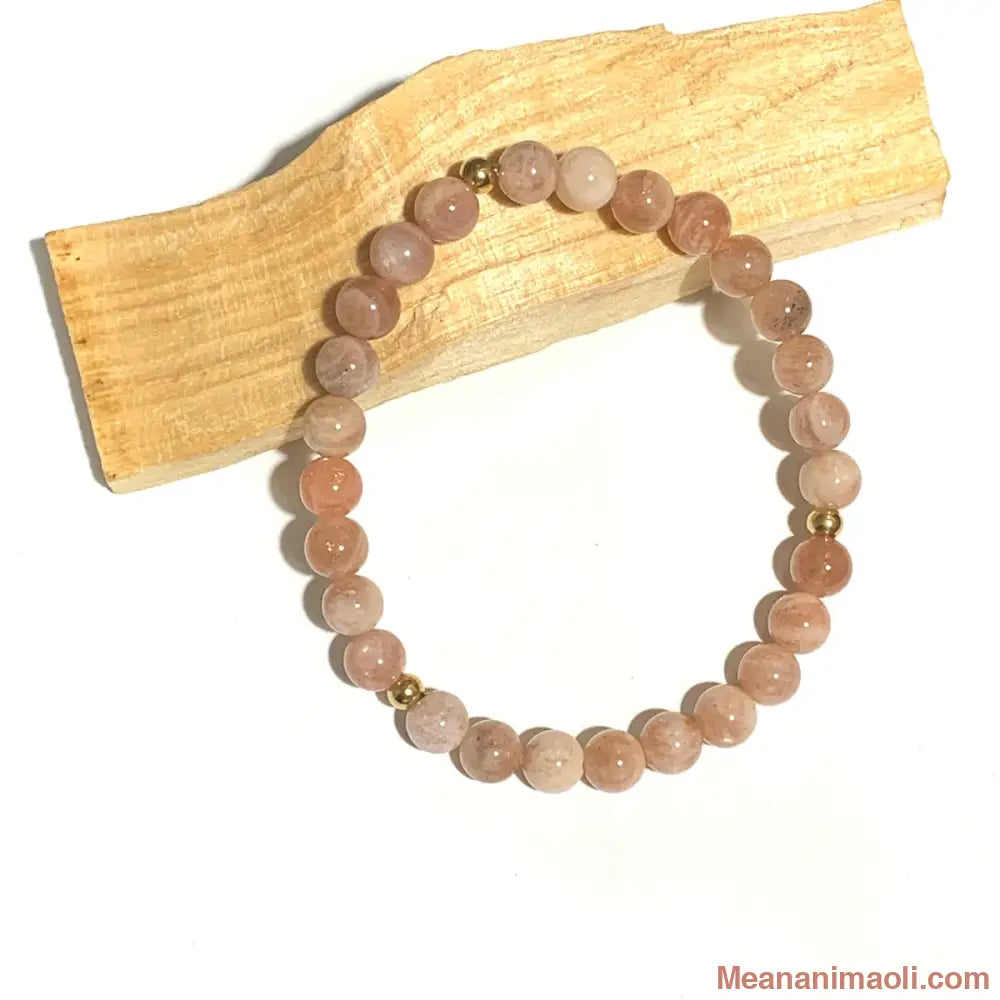 Bracelet en Pierre de Soleil 6mm, perles acier inoxydable doré posé sur un bâton de palo santo
