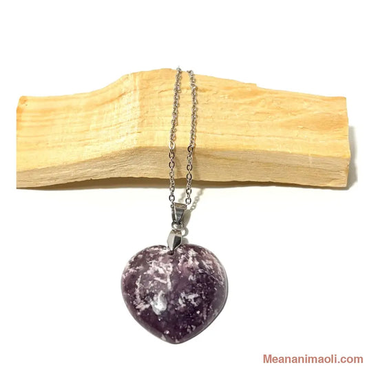 Collier en pierre naturelle Lépidolite en for de coeur avec bélière et chaîne en acier inoxydable argenté posé sur un morceau de bois palo santo, boutique MEANANIMAOLI.