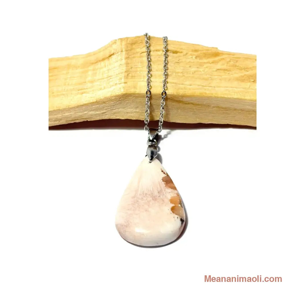 Collier en acier inoxydable avec son pendentif en Scolécite naturelle blanche et orangée posé sur un morceau de bois Palo Santo, une création MEANANIMAOLI.
