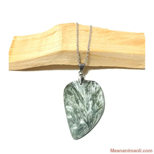 Pendentif en Séraphinite véritable avec reflets argentés et collier en acier inoxydable, posé sur bois de Palo Santo, boutique MEANANIMAOLI.
