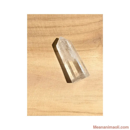 Pointe polie en Cristal de Roche naturel de Madagascar posée sur un support en bois clair. Dimensions : 4.5cm, Poids : environ 15g - MEANANIMAOLI.