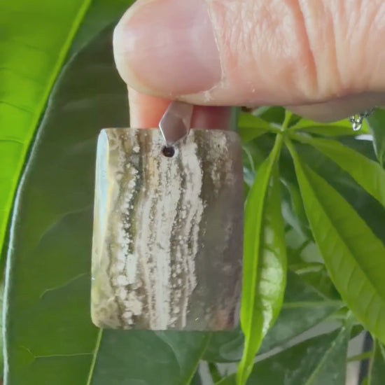 Vidéo d'un collier en Jaspe Océan naturel de forme rectangulaire, monté sur une chaîne en acier inoxydable. La vidéo met en valeur les motifs organiques verts et blancs uniques et les détails de la pierre par MEANANIMAOLI